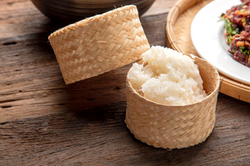 sticky rice in bamboo wicker box. thaifood menu. Thai sticky rice on wooden table background.