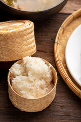 sticky rice in bamboo wicker box. thaifood menu. Thai sticky rice on wooden table background.