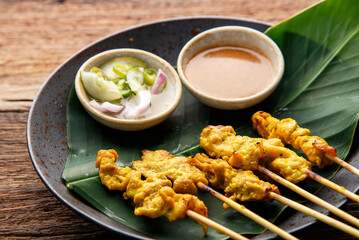 Thai Pork Satay, Moo Satay Grilled pork served with peanut sauce or sweet and sour sauce - Asian food Concept style on wooden table background. 
