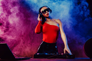 Sexy beautiful woman posing in headphones against abstract blue red background with smoke