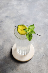 carbonated mineral water with lime and mint in the glass on gray background