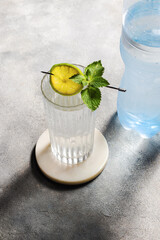carbonated mineral water with lime and mint in the glass on gray background. plastic bottle with water