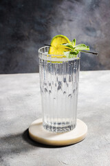 carbonated mineral water with lime and mint in the glass on gray background