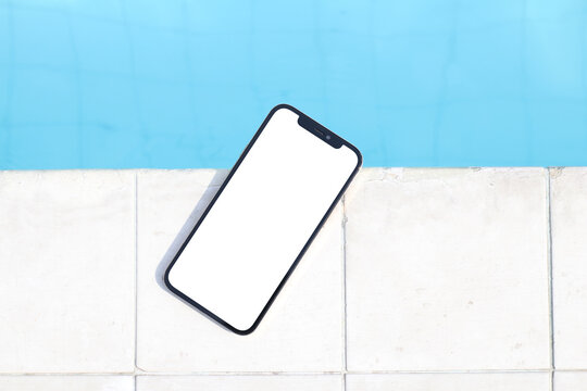 Mockup of a blank white screen smartphone close to a pool