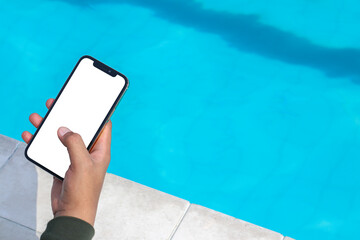 Mockup of a man browsing on to a white blank smartphone near a pool