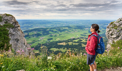 Naklejka premium nice senior woman hiking at Mount Gruenten in the Allgaeu Alps with awesomw view over Iller valley to Lake Alpsee and Lake of Constanz, Bodensee, Bavaria, Germany