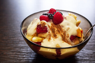 Fresh tasty fruit salad with yogurt on wooden table