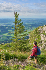 Fototapeta na wymiar nice senior woman hiking at Mount Gruenten in the Allgaeu Alps with awesomw view over Iller valley to Lake Alpsee and Lake of Constanz, Bodensee, Bavaria, Germany