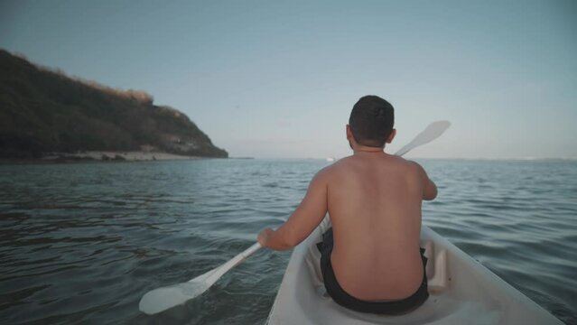 Indonesian Man Canoeing Paddling Canoe at Gunung Payung Beach, Bali, Indonesia Slow Motion