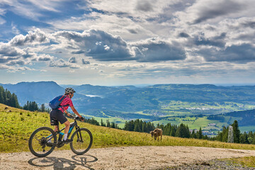 Fototapeta premium nice active senior woman riding her electric mountain bike at Mount Gruenten in the Allgaeu Alps , Bavaria, Germany