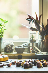 Figs on kitchen table with  baking utensils at window background Preparing Mediterranean fruit. Front view.