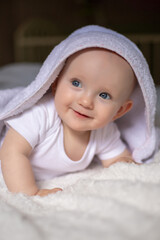 smiling baby looking at camera under a white blanket, towel. selective focus