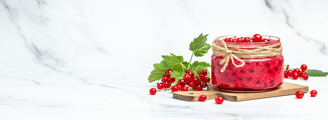 red currant jam in jar. Canned fresh berries on a light background. Long banner format