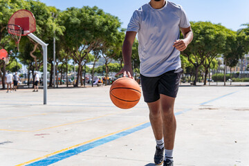 Unrecognizable young muslim man playing basketball in the street, city life and training and sport concept