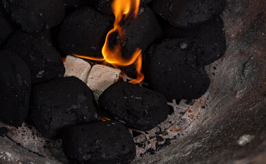 Lighting a barbecue fire. Briquette and white cube grill lighter. Flame with charcoal.