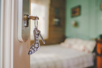 Hotel room and keys in the door with a keychain - a stylized woman's high-heeled shoe....