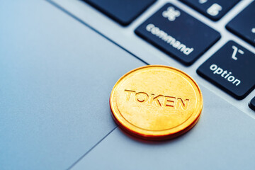 Text Token written on a golden coin lying on the modern laptop. Concept of cryptocurrency, digital...