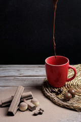 hot chocolate dripping into a red cup, along with a variety of chocolates to taste. international chocolate day.