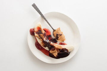 Loaded Banana Sundae Topped with Peanut Butter, Strawberry Syrup and Chocolate Syrup