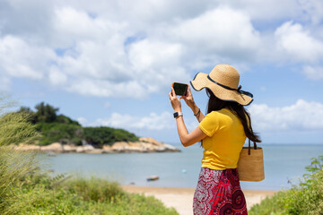 Woman use mobile phone to take photo of the sea