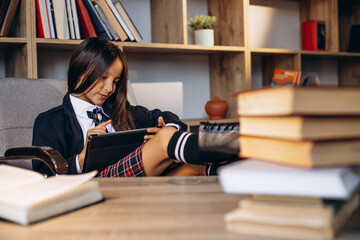 Pretty school girl reading books at the library