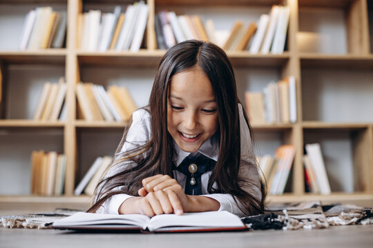 Pretty school girl reading books at the library