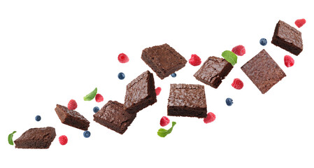 Slices of delicious chocolate brownie with fresh berries and mint flying on white background....