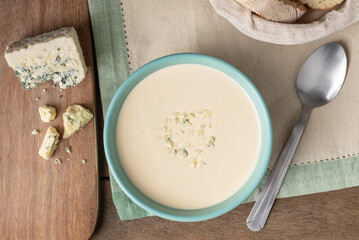 Cheese soup in a bowl with bread slices over wooden table