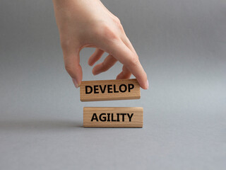 Develop agility symbol. Concept word Develop agility on wooden blocks. Beautiful grey background. Businessman hand. Business and Develop agility concept. Copy space