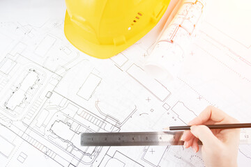 Architect working on blueprint, with architectural project at construction site at office desk in office