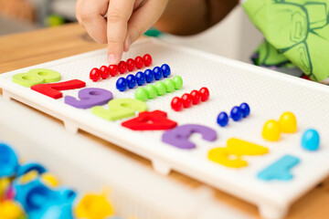 by provided numbers boy inserting pins. counting game. mathematical task. play at home. way of learning.