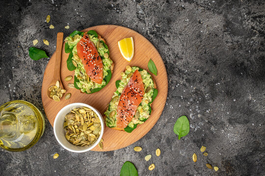Delicious breakfast or snack sandwich salmon, avocado, spinach, nuts, sunflower seeds, toast with red fish and guacamole. Healthy, clean eating. Vegan or gluten free diet. top view, copy space