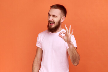 Portrait of bearded man standing with thumbs up, like gesture, demonstrating approval and agree...
