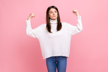 Confident energetic stylish woman raising hands showing biceps, expressing power, female rights,...
