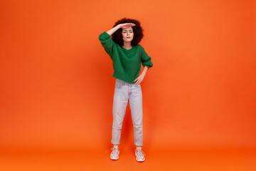Full length portrait of curious woman with Afro hairstyle wearing green casual style sweater...