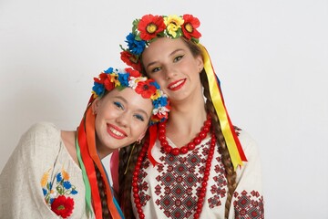 Two Beautiful Ukrainian girls in national costumes vyshyvanka. Studio shoot on white background. Vse bude Ukraine. We`re together