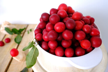 large white bowl with wild cherry plum, fresh juice fruit and berry on wooden boards, concept of healthy eating, vegan diet, raw food, healthy food, ingredients for making tkemali sauce
