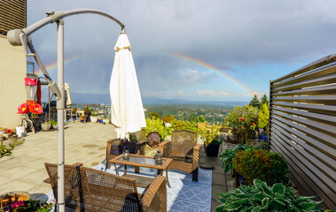 Rooftop patio garden enjoying spectacular view of rainbow over Fraser Valley, BC, after a flash rainstorm.