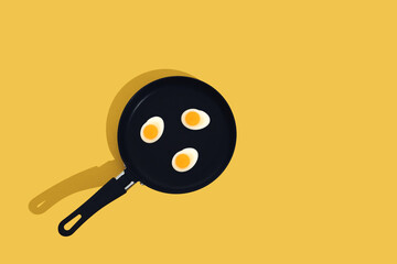 Creative food concept with gummy candy fried egg shaped on black frying pan over yellow background....