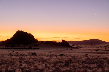 African sunset with mountains and grass plains and moon