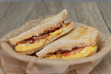 Grilled breakfast sandwich with scrambled eggs, bacon, and cheese on sour dough toast bread