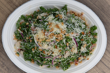 Enormous kale salad piled high with chopped vegetables, pine nuts, parmesan, and pecorino cheese for a health conscious diet.