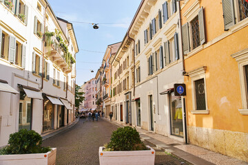 Fototapeta na wymiar Verona, Italy - October 12, 2021: Narrow sunny cobblestone street in Verona