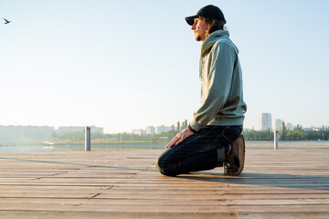Morning meditation in the park on the lake, the guy kneeling on the wooden floor, the practice of...
