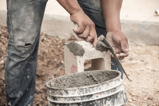working man's hands putting cement on a spatula