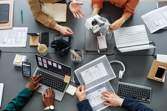 High angle view of team of developers testing new application for virtual reality glasses at table during a meeting