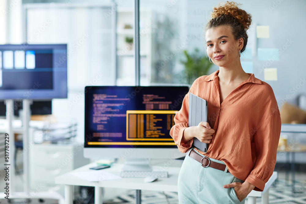 Wall mural portrait of young female programmer with digital tablet looking at camera while standing at her work