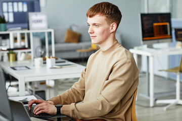 Young man working as a programmer, writing programming code on computer at the coworking space