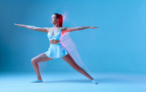 Amazing white girl in sports uniform exercises. Isolated image of a sports model on a blue background.