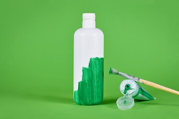 Greenwashing concept with white plastic bottle being painted green